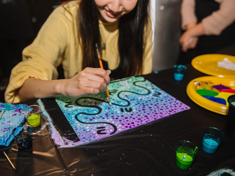 A close up of a person painting a colourful abstract picture